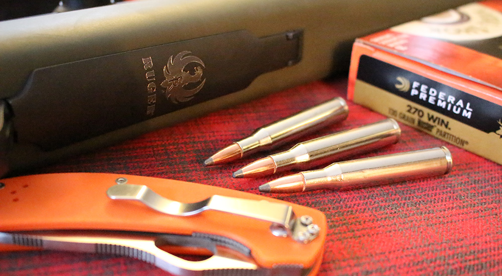 Federal Premium .270 Winchester ammunition laying next to Ruger rifle.