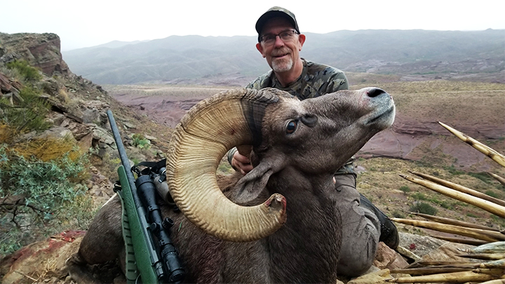 Hunter with Desert Bighorn Ram on mountain