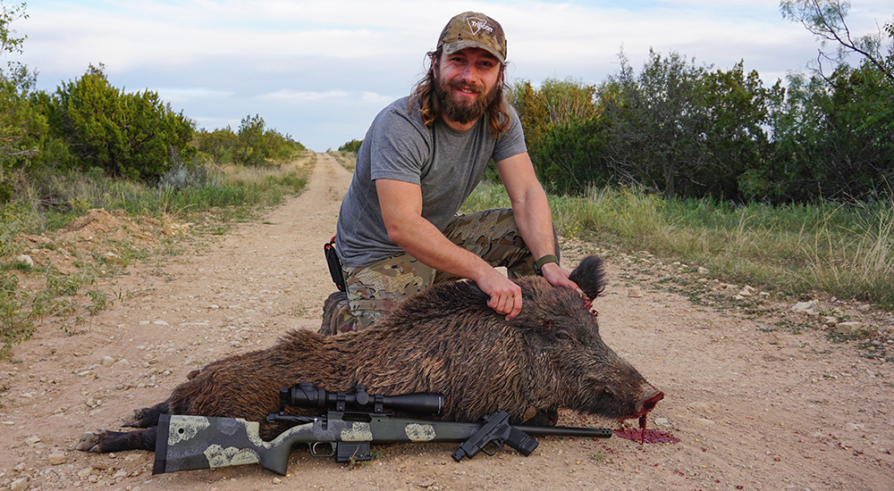 Male hunter posing with feral hog in Texas.