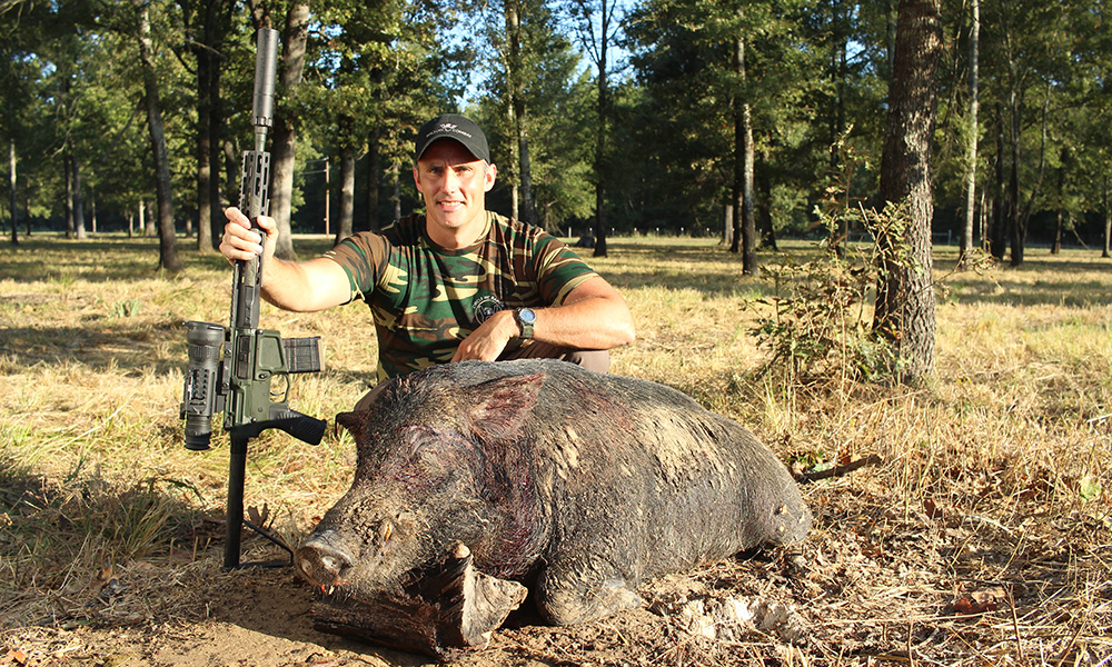 Hunter posing with feral hog while holding Wilson Combat .300 HAM'R rifle.