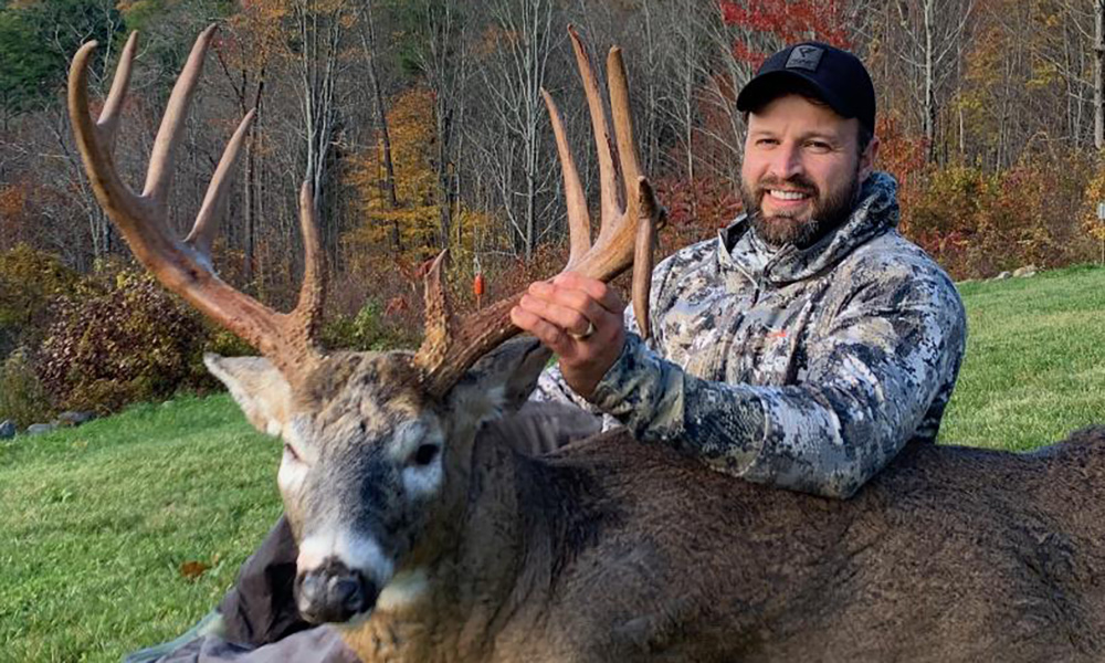 Male hunter holding large whitetail buck killed in Merrimack County, New Hampshire.