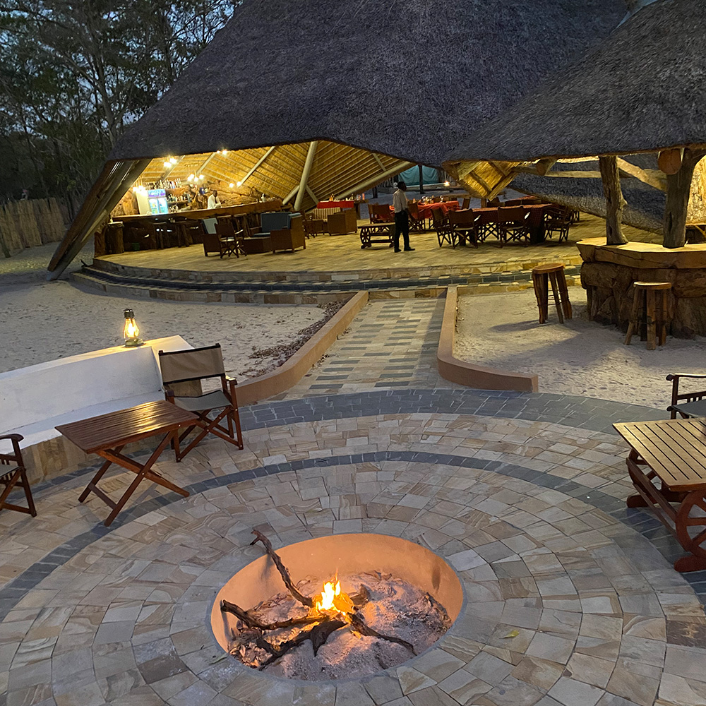 Tanzania hunting camp with thatch roof dining area and fire pit.