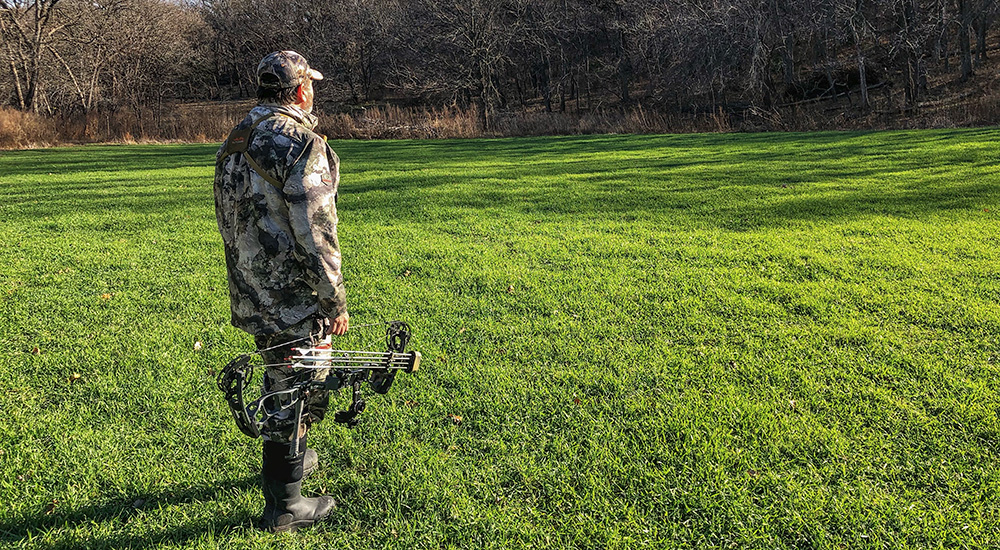 Bowhunter surveying edge of field for best stand placement.