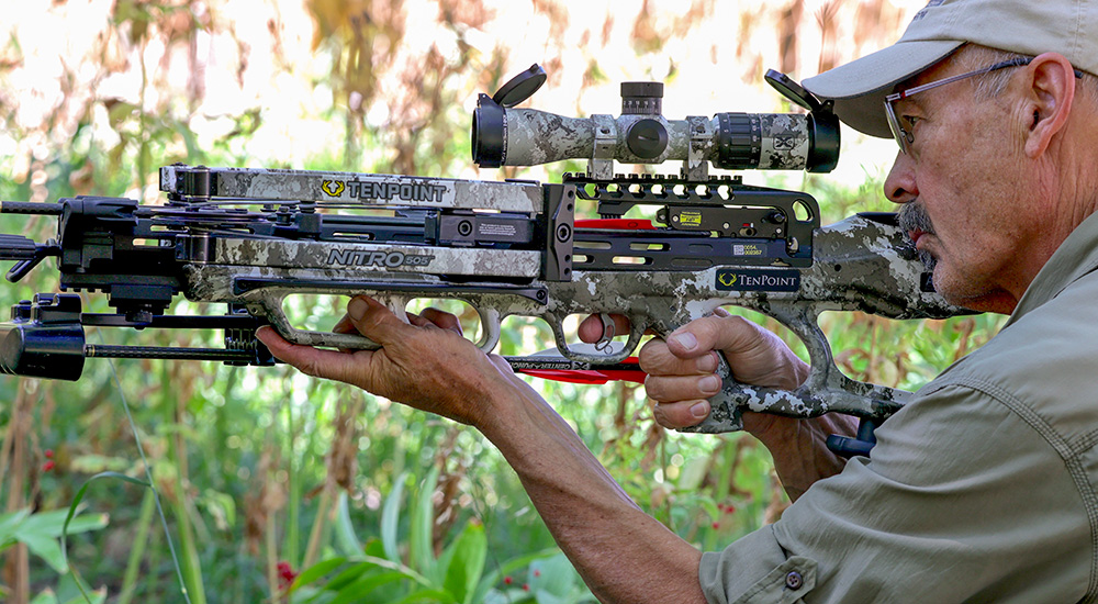 Male hunter holding up TenPoint crossbow preparing to pull the trigger.