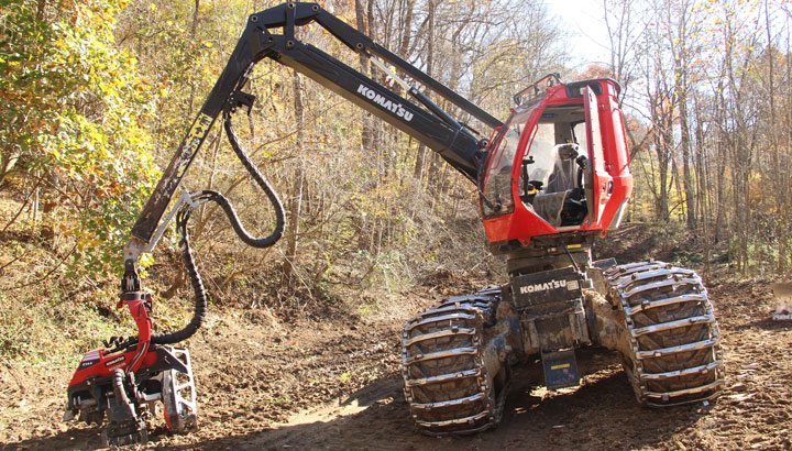 Red Komatsu with its arm extended forming a triangle with the ground.