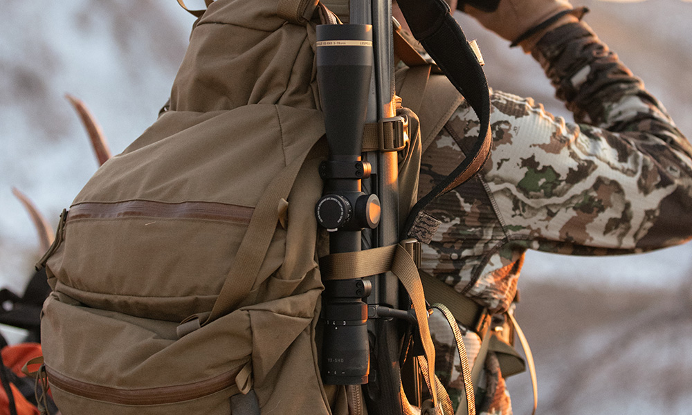 Rifle strapped in hunting pack worn on back of hunter.
