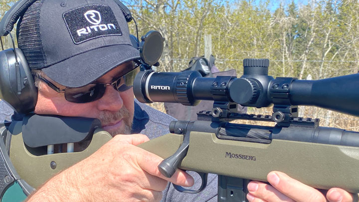 Man shooting a mossberg adorned with a Riton X5 from a bench.