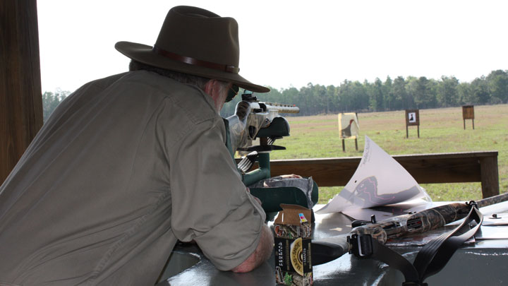 Man pattern-testing a shotgun off a bench.