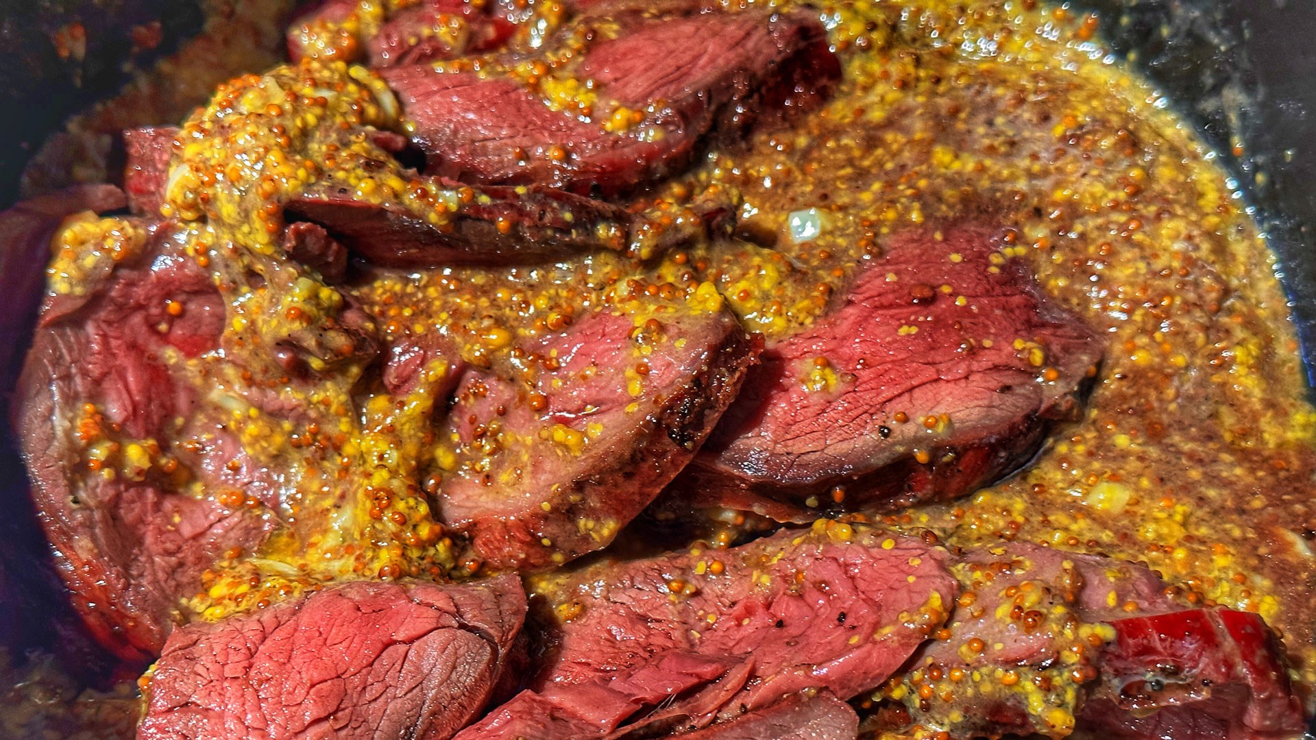 Rare pink venison doused in mustard sauce