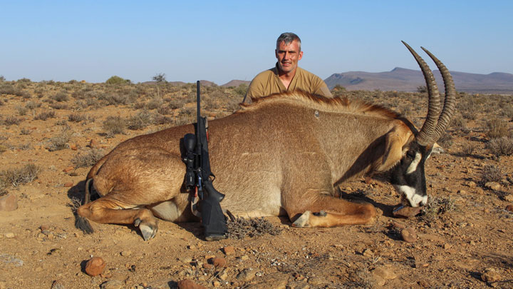 Hunter with massive Oryx down on African plain