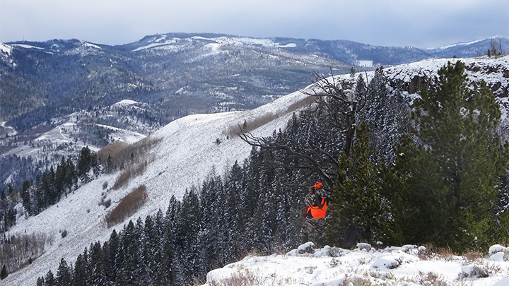 Hunter glassing vast, open snow-covered mountains in the West