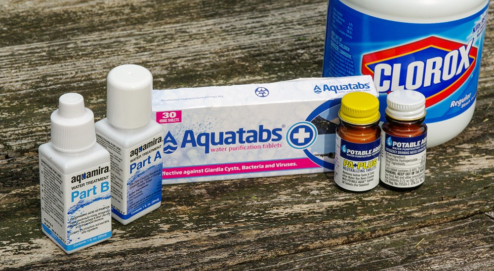 Water purification tablets and bleach on picnic table.