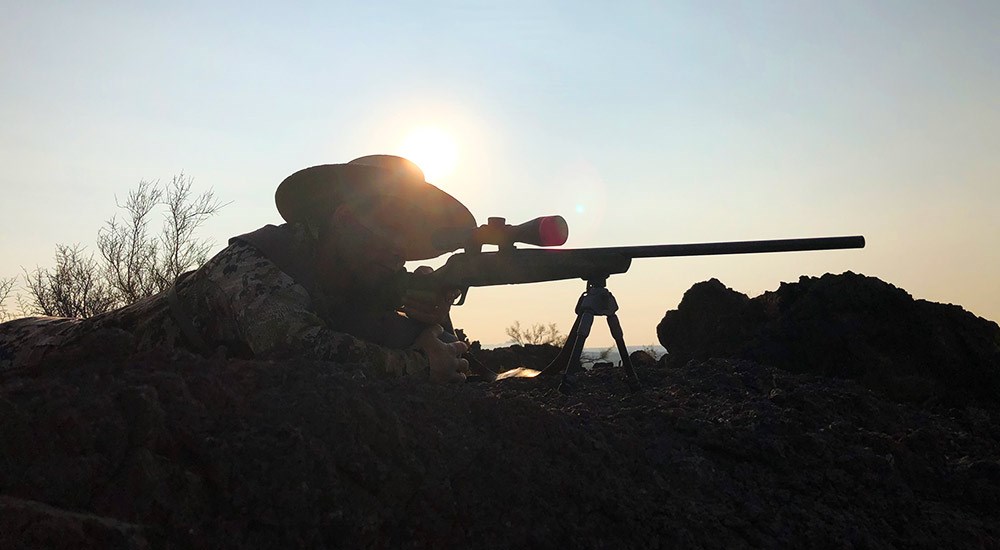 Hunter Shooting Rifle on Ridge-top