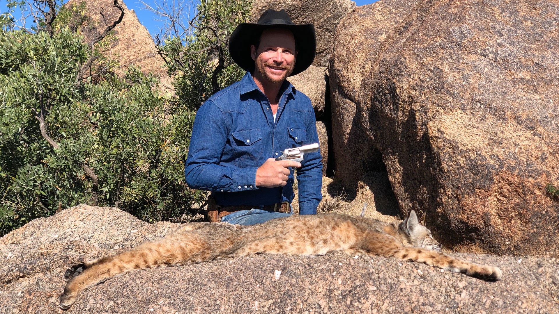 Author poses with pistol over bobcat