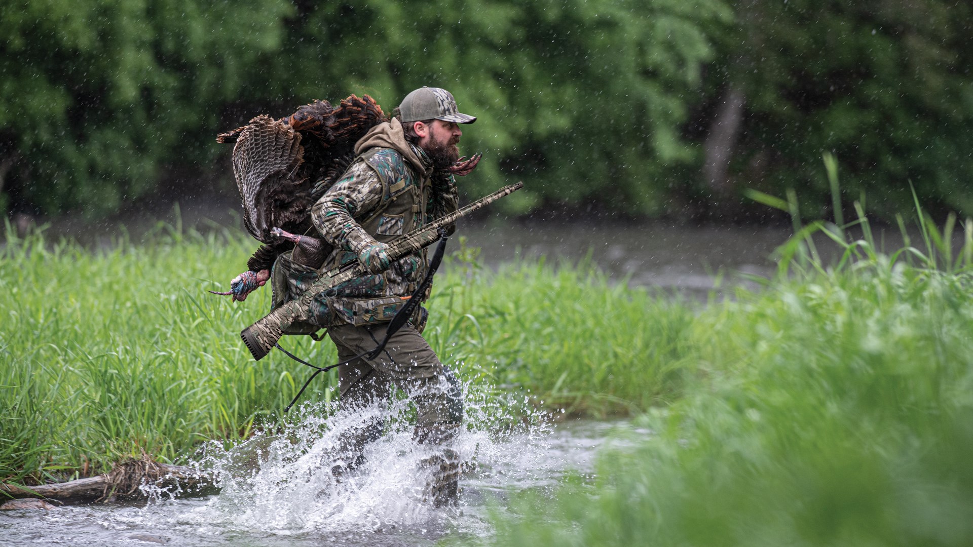 Hunter crossing stream with a turkey