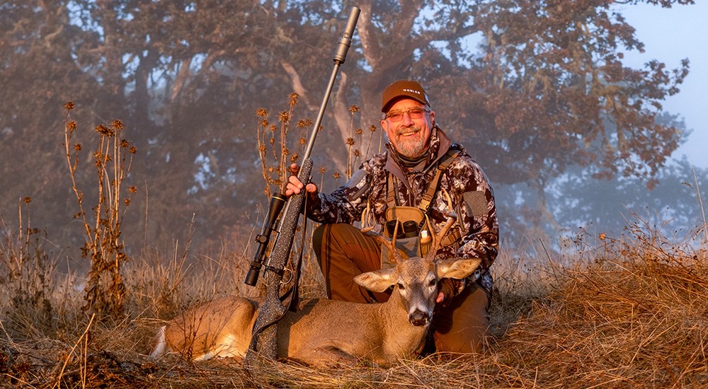 Male hunter posing with Columbia whitetail deer in Oregon.