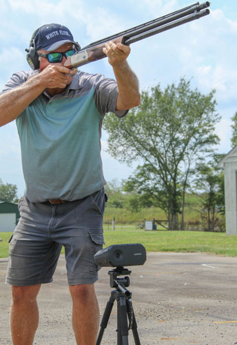 Man in blue shirt and shorts utilizing Garmin Xero S1 while trapshooting.