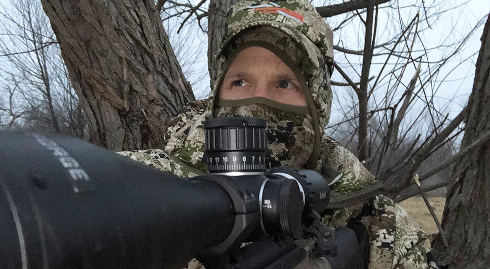 Hunter in camouflage looking down rifle scope.