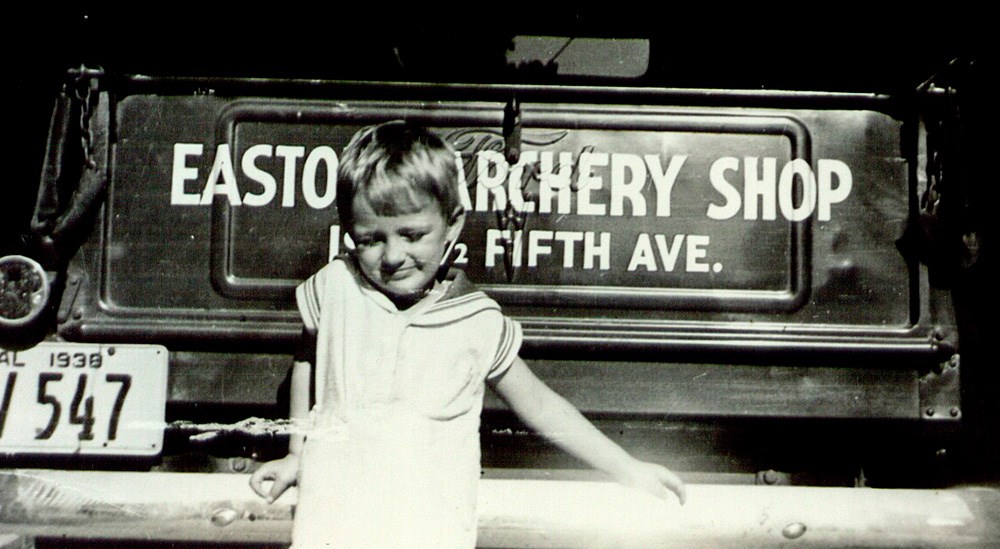 Young boy standing behind Easton Archery Shop truck.