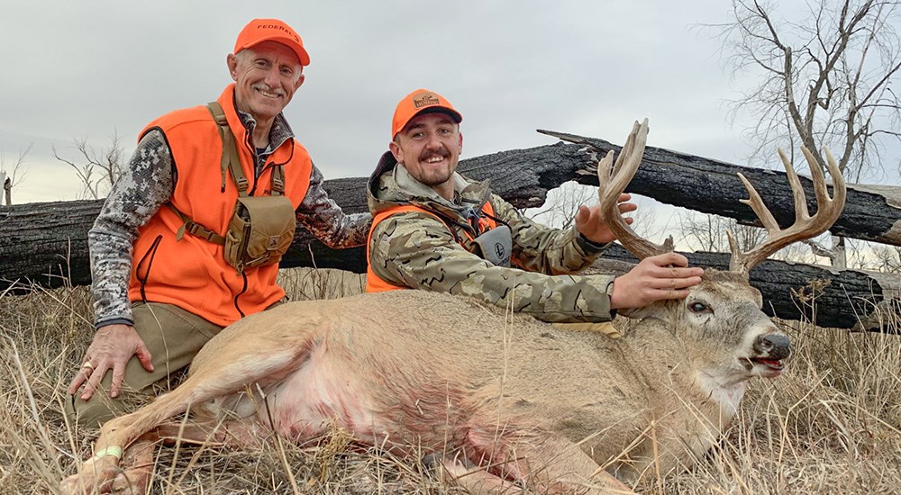 Two male hunters posing with white-tailed deer in Kansas.