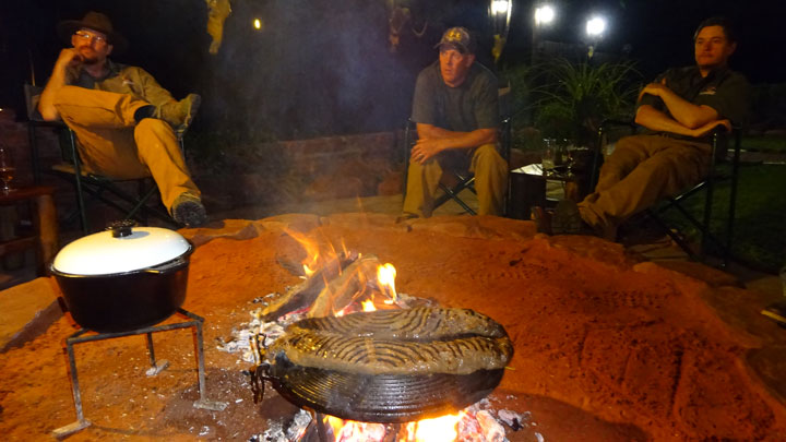 Three hunters enjoying some camaraderie by a fire.