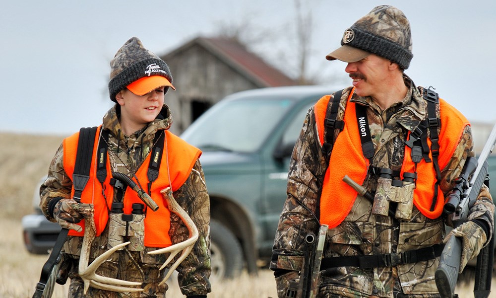 Father and son deer hunting wearing in camouflage and blaze orange