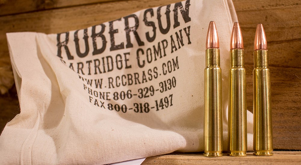 Three .350 Rigby Magnum ammunition cartridges on wooden table.