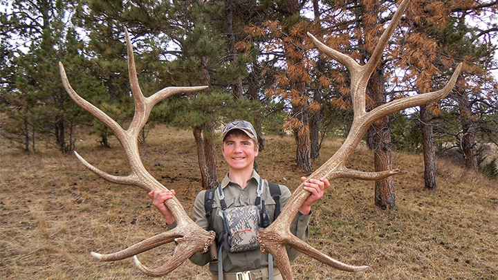 Young man with pair of shed elk antlers found in dark timber