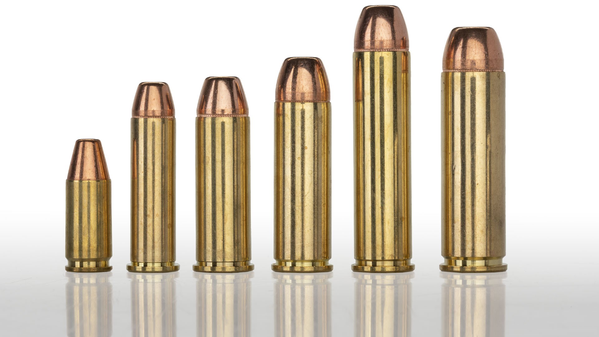 Hornady Backcountry Defense ammunition cartridges picket fence arrangement brass bullets row standing erect shadow on white table white background