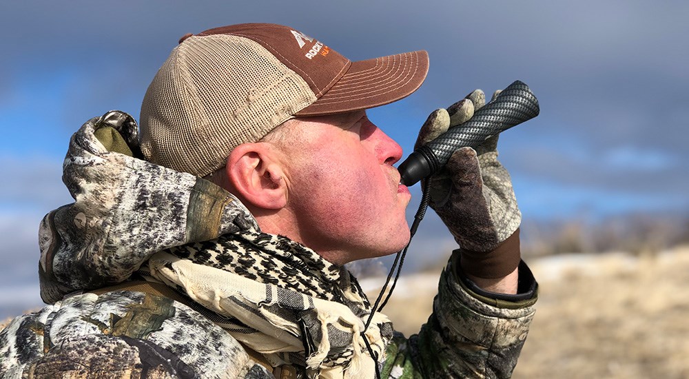 Male hunter using coyote mouth call.