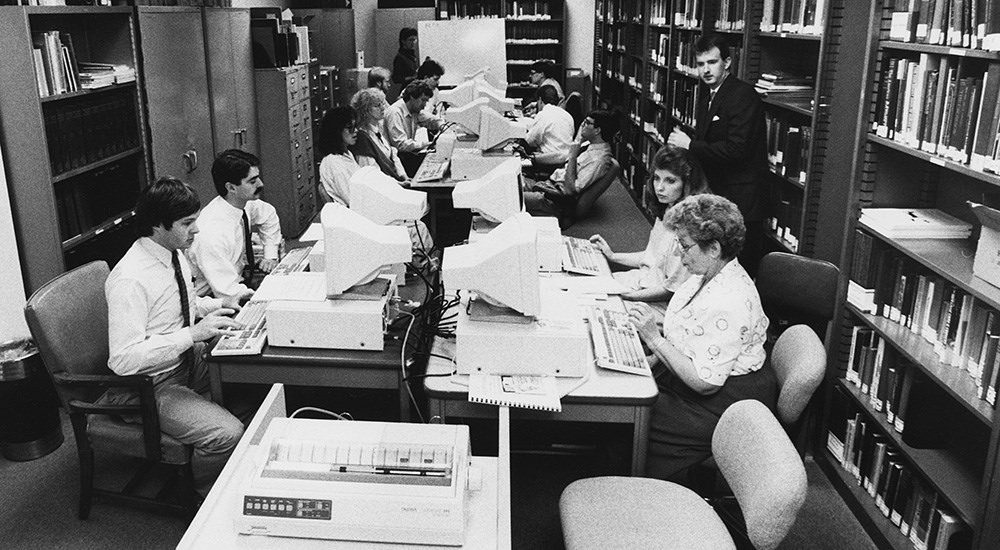 Editors learning digital publishing methods in large office space in 1990s.