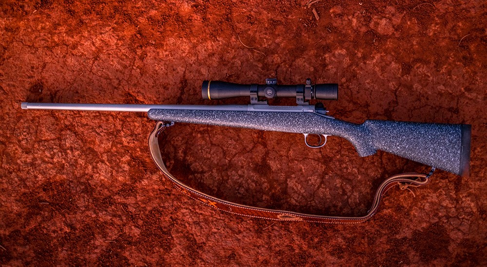 Nosler Model 21 bolt-action rifle on red clay dirt.