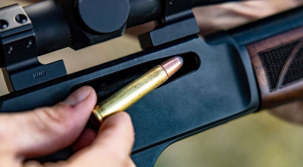 Remington 360 Buckhammer ammunition cartridge being loaded into lever action rifle.