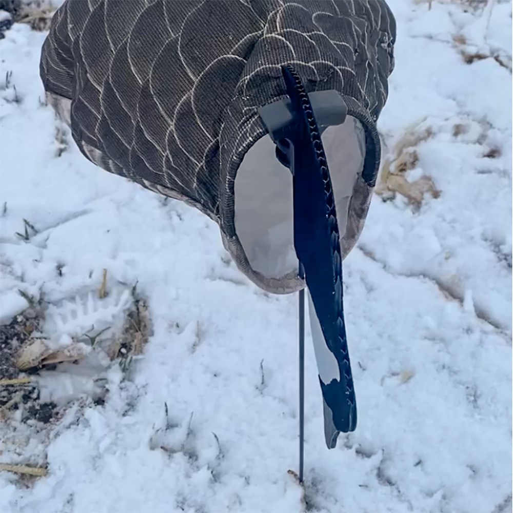 Goose sock decoy on stake in snowy ground.