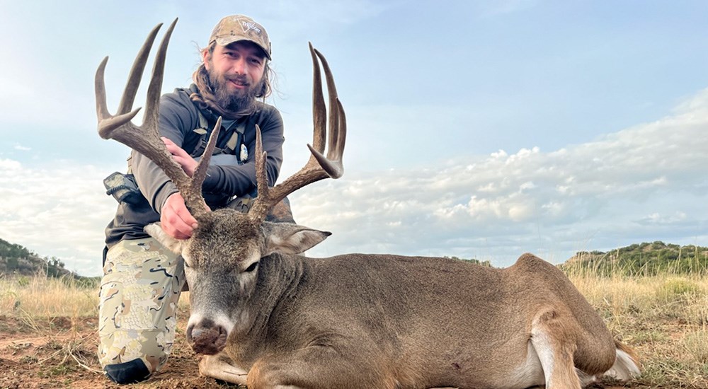Male hunter posing with whitetail buck harvested in Texas.