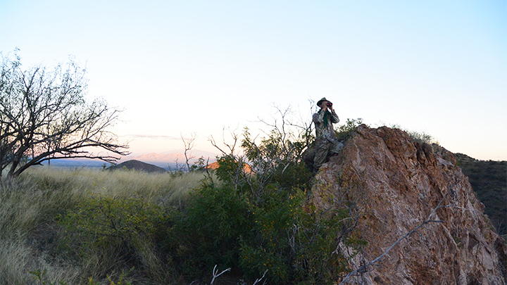 Hunter on mountain looking through binoculars