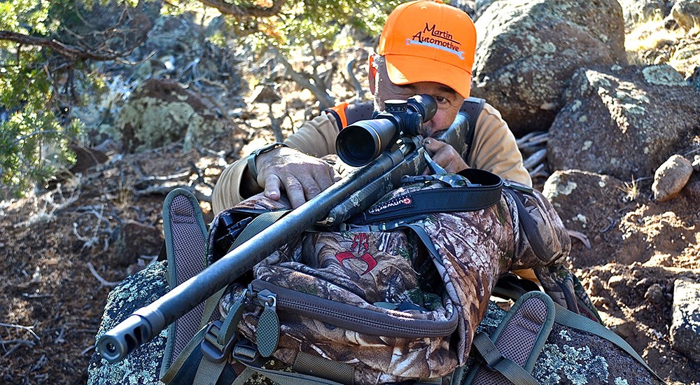 Male Hunter Shooting Rifle off of Hunting Pack