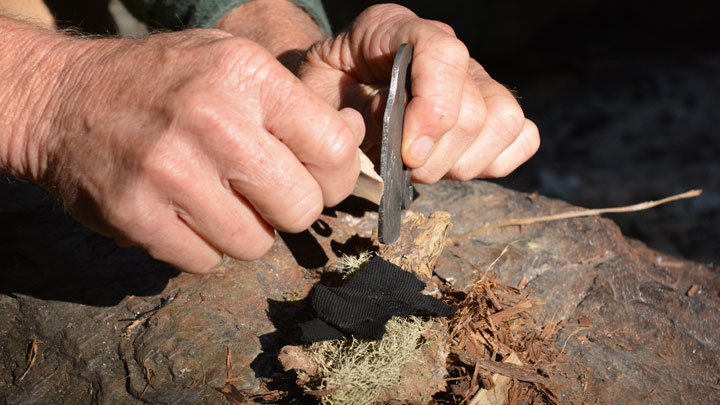 Striking a flint into a char cloth.