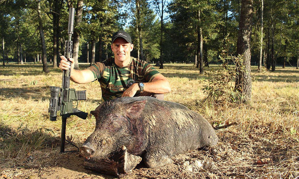 Hunter posing with feral hog while holding Wilson Combat .300 HAM'R rifle.