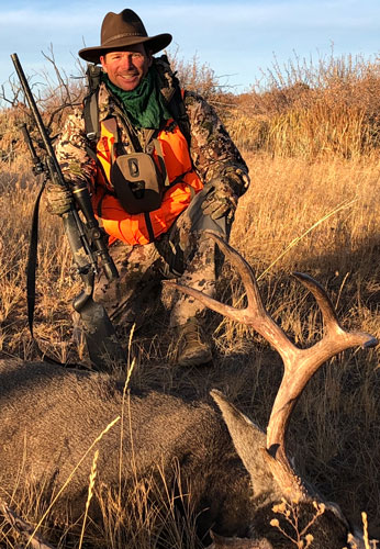 A hunter stands behind a downed buck
