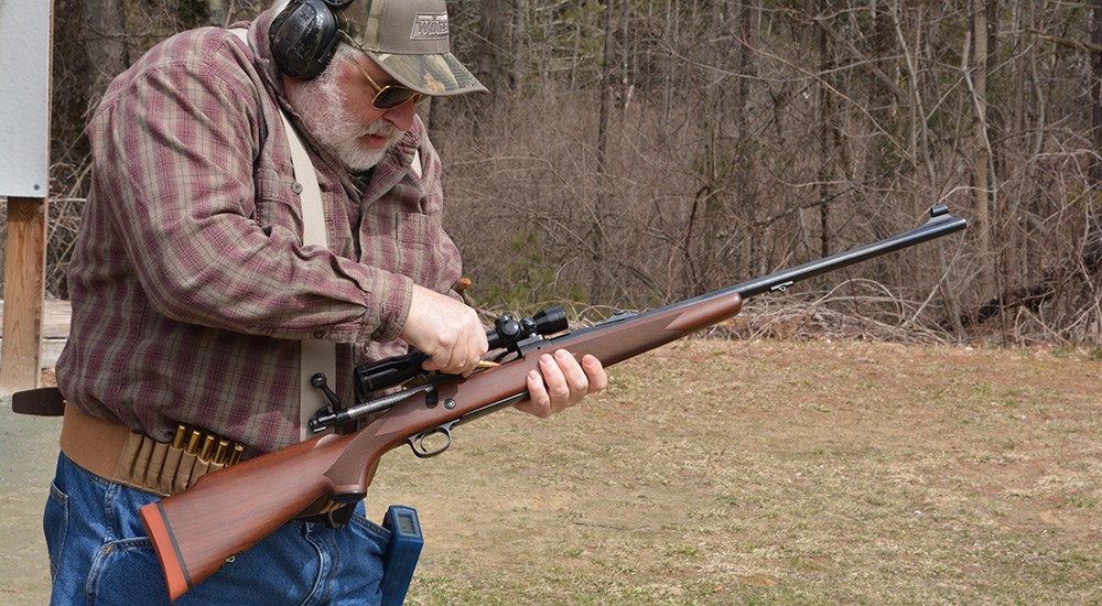 Man on shooting range loading bolt action rifle