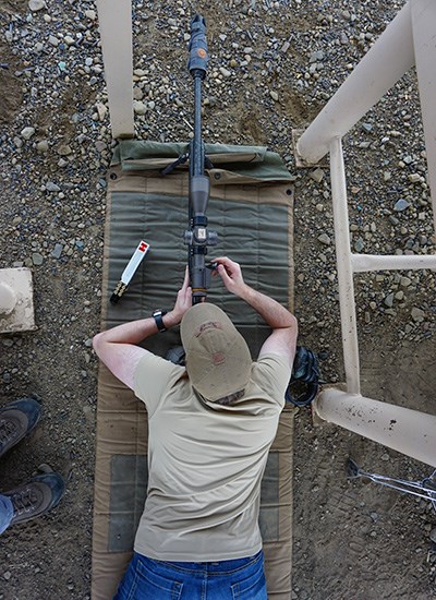 Male shooting bolt action rifle in prone position on rifle range.