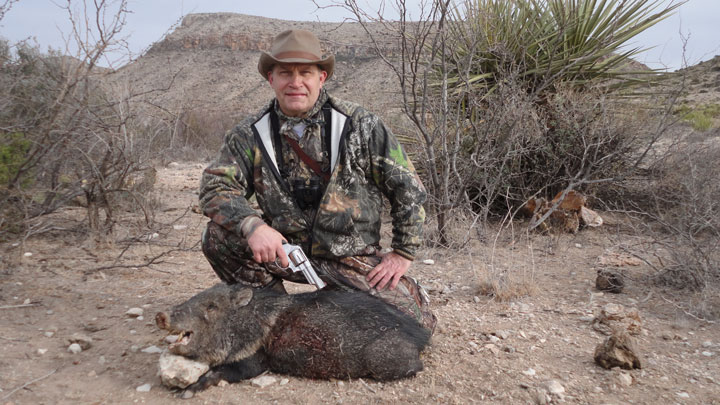 Hunter poses with a downed javelina, draping his pistol over its back