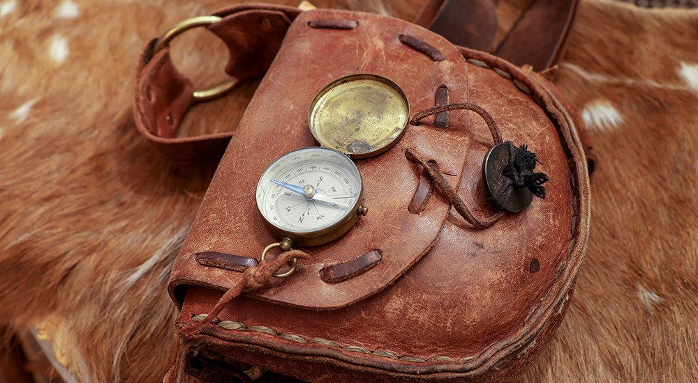 Open compass on leather satchel.