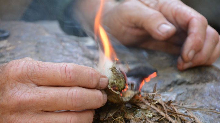 The char cloth ignites into a plume of brilliant yellow-red flame