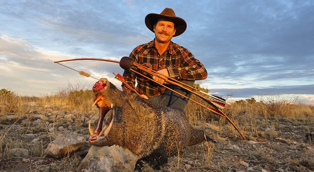 Male traditional bowhunter posing with javelina.