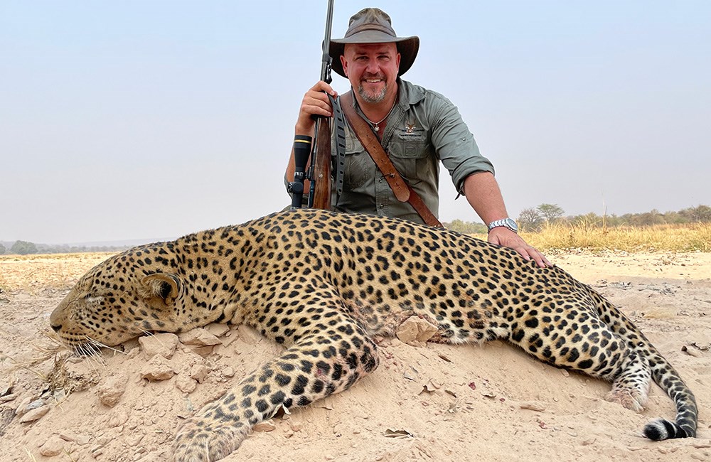 Male hunter posing with leopard.