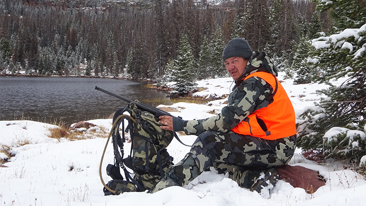 Hunter in snow near creek hunting the West