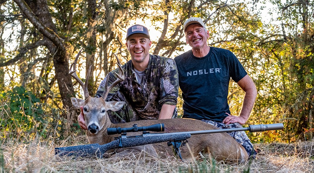 Male hunters posing with Columbia whitetail buck and Nosler Model 21 rifle.