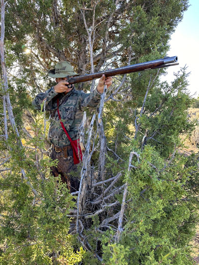 Hunter shooting muzzleloader from cover